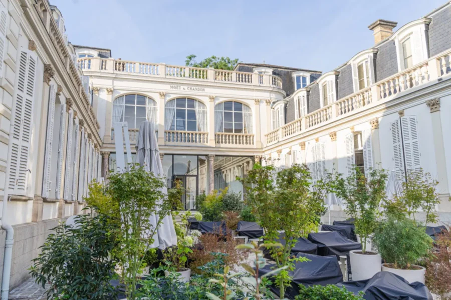 Moet & Chandon Reims courtyard at champagne house with covered seating and planters.