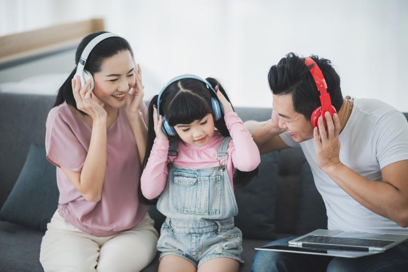 Mom and dad with female chid are listening to music with wireless headphones