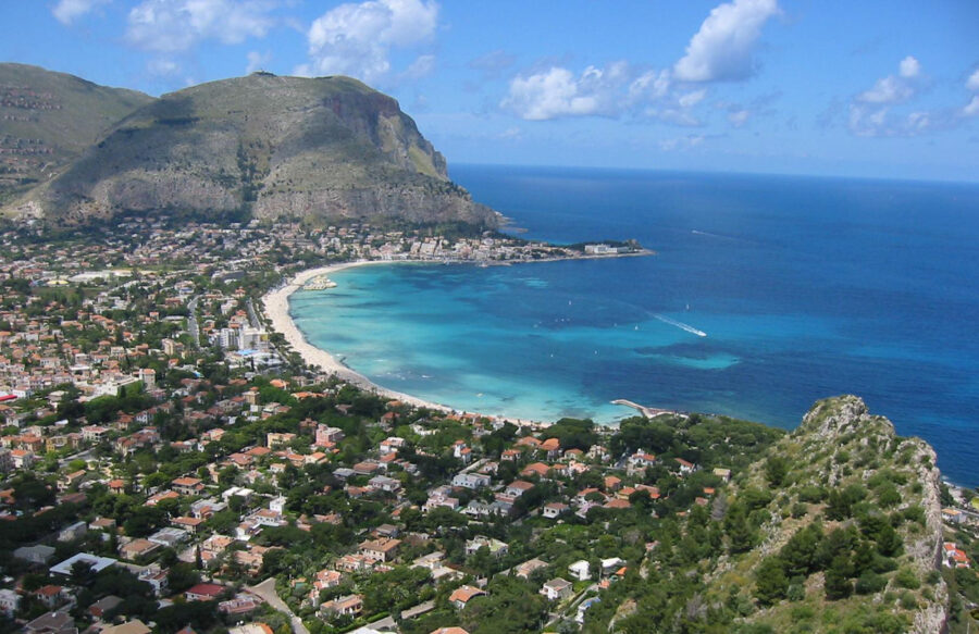 Scenic view of Mondello beach in Palermo, Italy, featuring golden sands and clear blue waters under a sunny sky