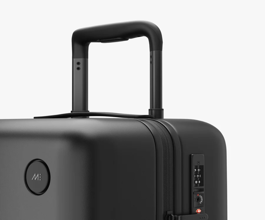 Black Monos carry-on suitcase with wheels on a white background.