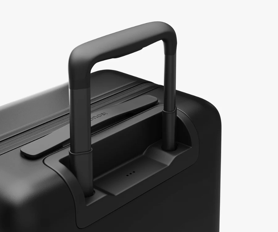 Black Monos carry-on suitcase with a handle, set against a clean white background.
