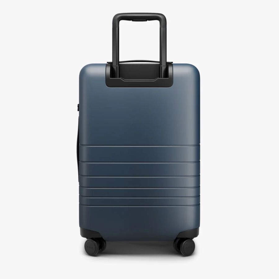 Blue Monos Carry-On Pro suitcase with wheels, featuring a back and handle, set against a white background.