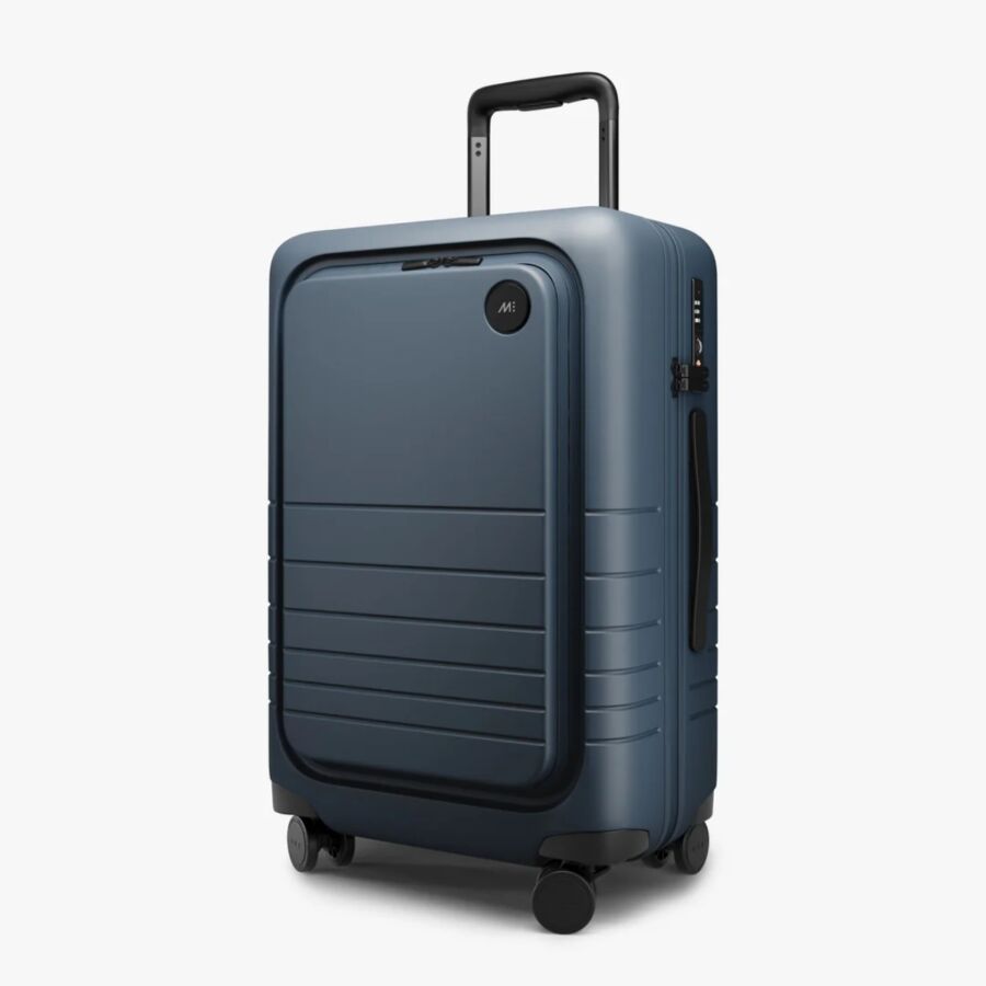Side view of a blue Monos Carry-On Pro suitcase with wheels on a clean white background.