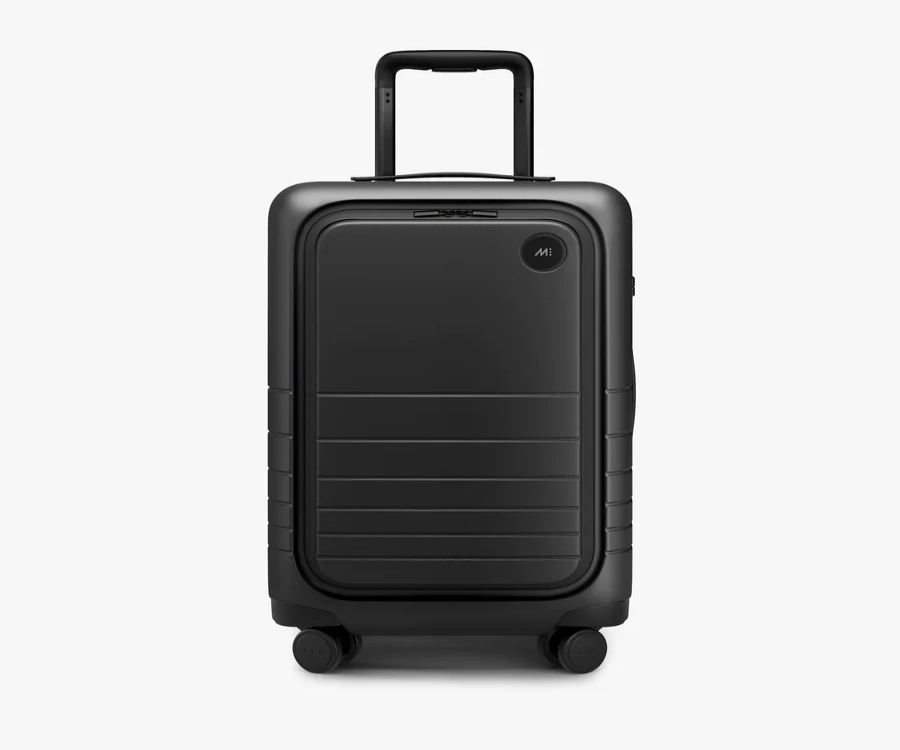 Monos Carry-On Pro, a black suitcase with wheels, displayed against a white background.