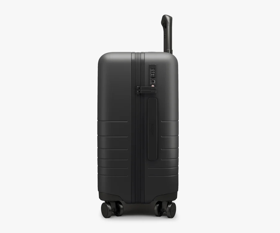 Black Monos Carry-On suitcase with wheels, displayed on a white background.
