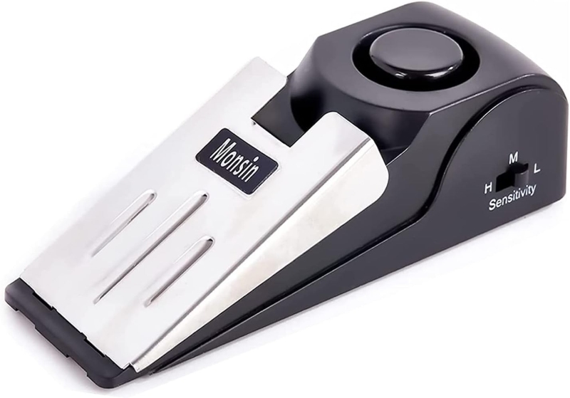 Black and silver doorstop alarm with a wedge shape, featuring a round button and sensitivity switch labeled "Monsin."