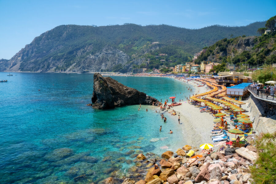 Summer view of Monterosso al Mare, a charming town in Cinque Terre, Italy, featuring colorful buildings and beachgoers