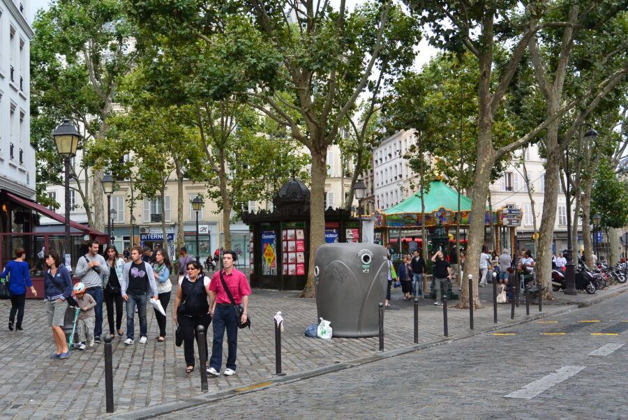 Montmartre Place des Abbesses Paris cobblestone square with kiosk, carousel, trees, people.
