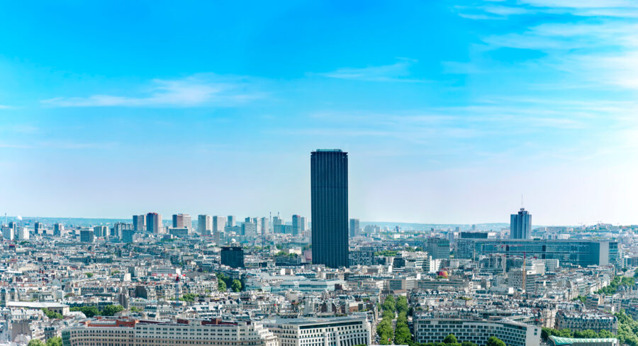 Panoramic aerial shot of Montparnasse tower and the Paris skyline on a clear, sunny day.