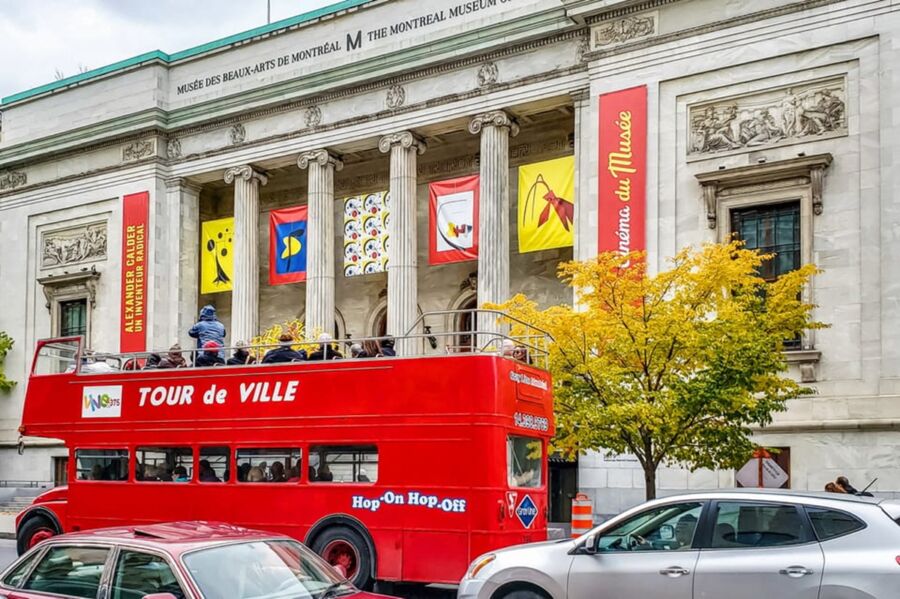 Facade of Montreal Museum of Fine Arts with tours bus and vibrant banners in autumn.