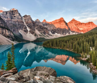 Sunrise over Moraine Lake in Banff National Park, showcasing vibrant colors reflecting on the calm water and surrounding peaks.