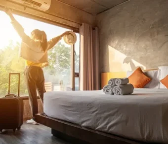 Traveler enjoying morning sunshine in modern hotel room with lush view and stylish design.