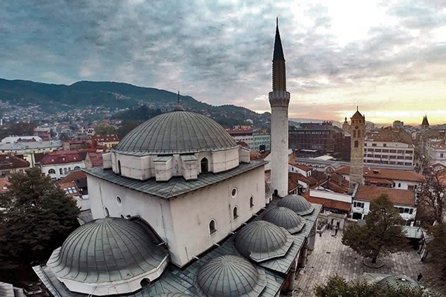 Panoramic cityscape featuring prominent mosque with domes, minaret, and historical architecture.
