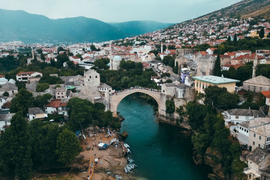 Aerial view of Mostar featuring Stari Most bridge and Ottoman architecture along Neretva River.