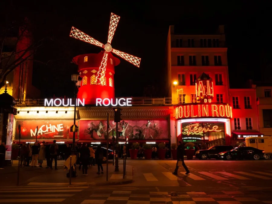 Iconic Moulin Rouge in Paris at night, illuminated, bustling street, vibrant nightlife, cultural landmark.