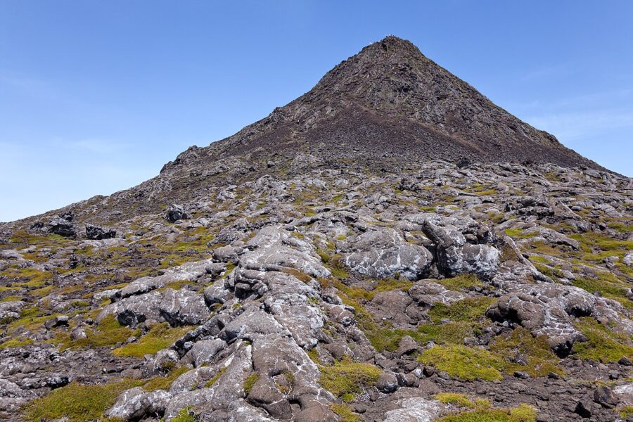 Mount Pico in Portugal, featuring rocky terrain and patches of grass atop the mountain.
