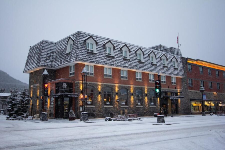 Mount Royal Hotel in Banff, Canada, surrounded by snow, features a striking red roof against a winter landscape.
