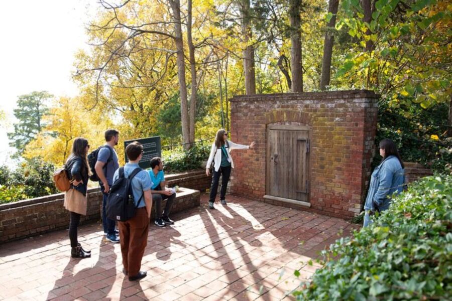 Tourists standing around a brick wall, enjoying a Mount Vernon day trip that includes a river cruise and guided tour.
