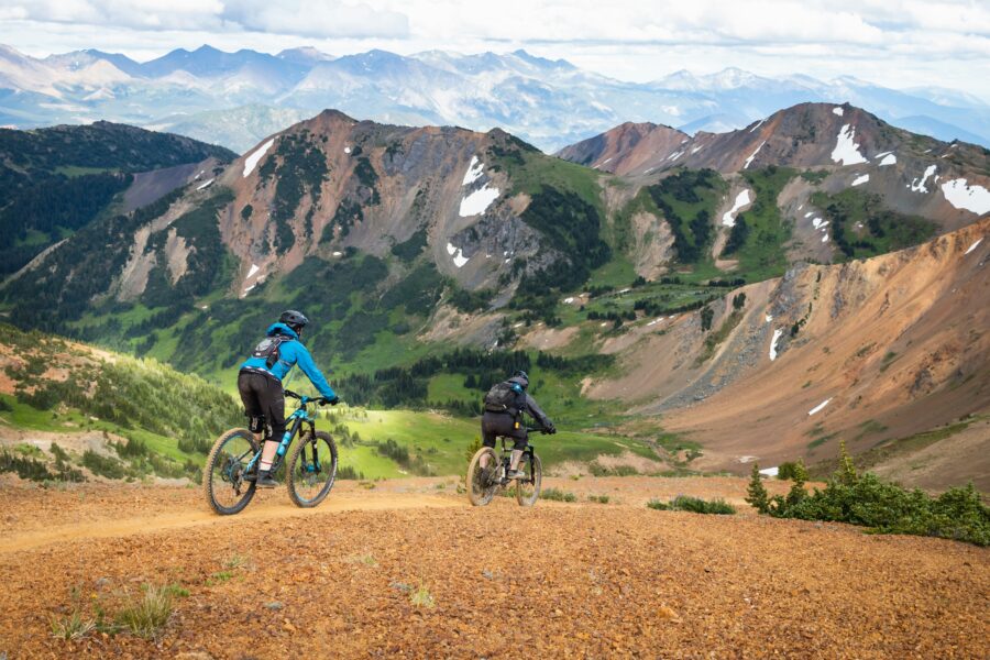 Mountain bikers on a rugged trail with breathtaking mountain and valley landscape.
