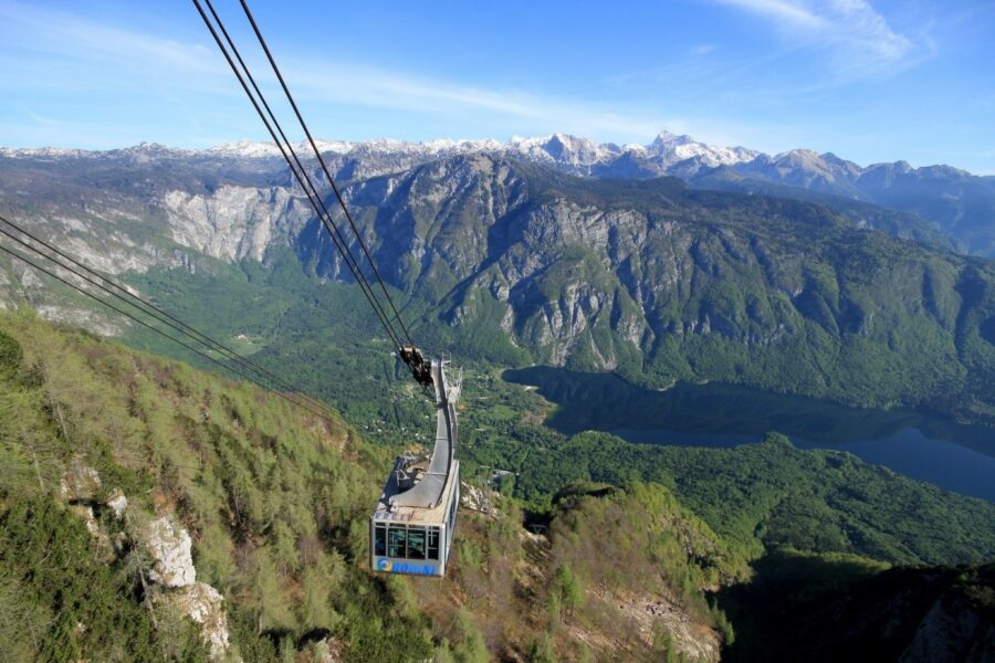Vogel cable car over alpine valley with lake and snow-capped peaks.