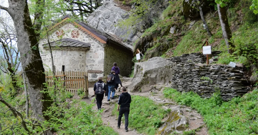 Stone mountain chapel on rocky hiking trail with hikers near Cave of St. Ivan Rilski.