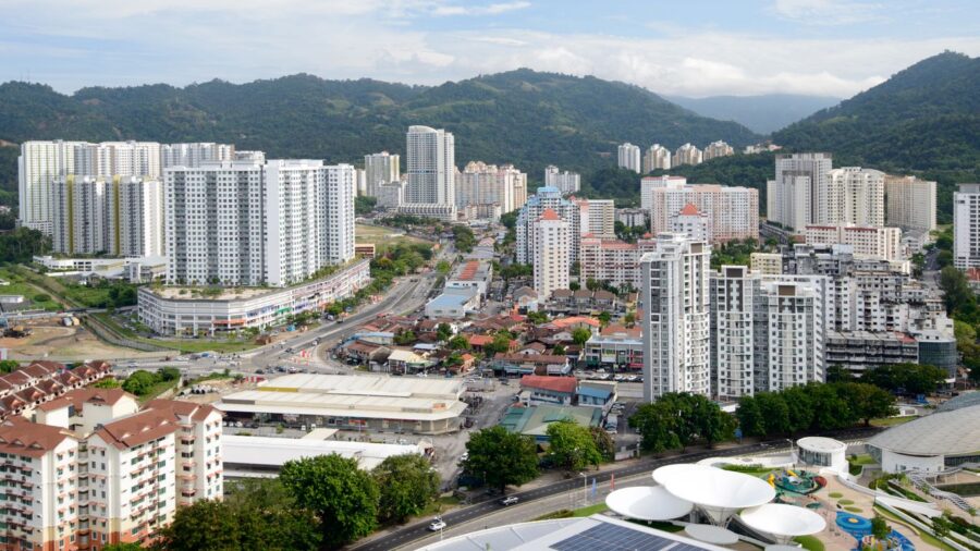 High‑rise city skyline in Bayan Lepas valley with mountains, dense apartments, roads, and greenery.