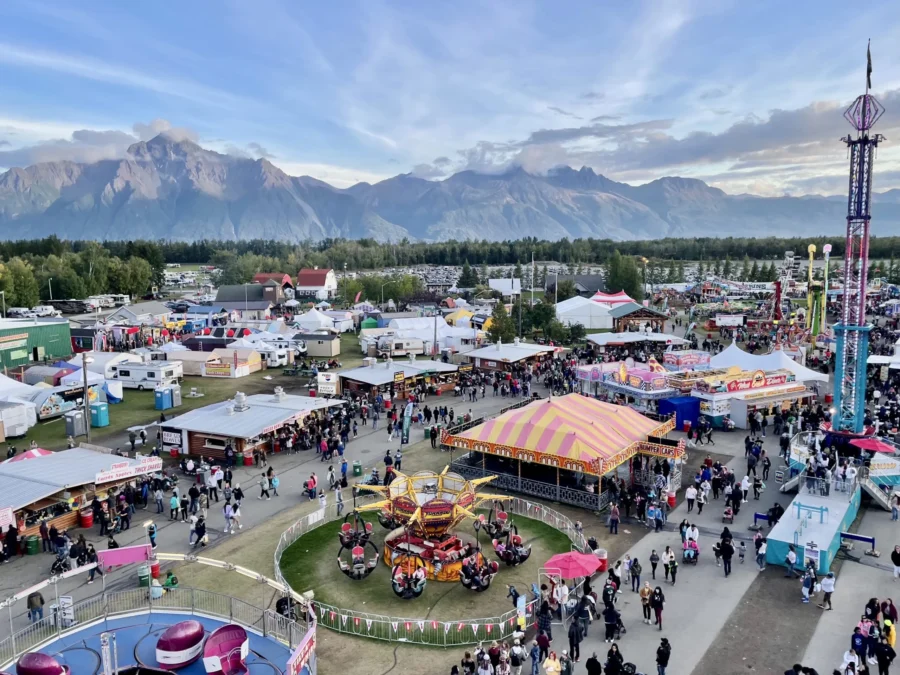 Southeast Alaska State Fairgrounds with carnival rides, RVs, and mountain panorama at dusk.