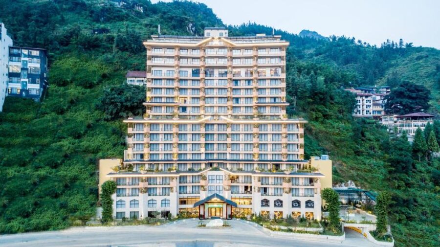 Terraced luxury mountain hotel in Sapa, Vietnam nestled on a green hillside at sunset.
