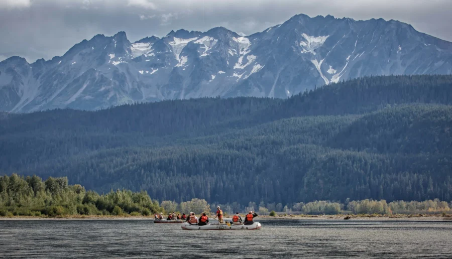Chilkat River rafts on calm Alaskan lake beneath snow-capped mountains.
