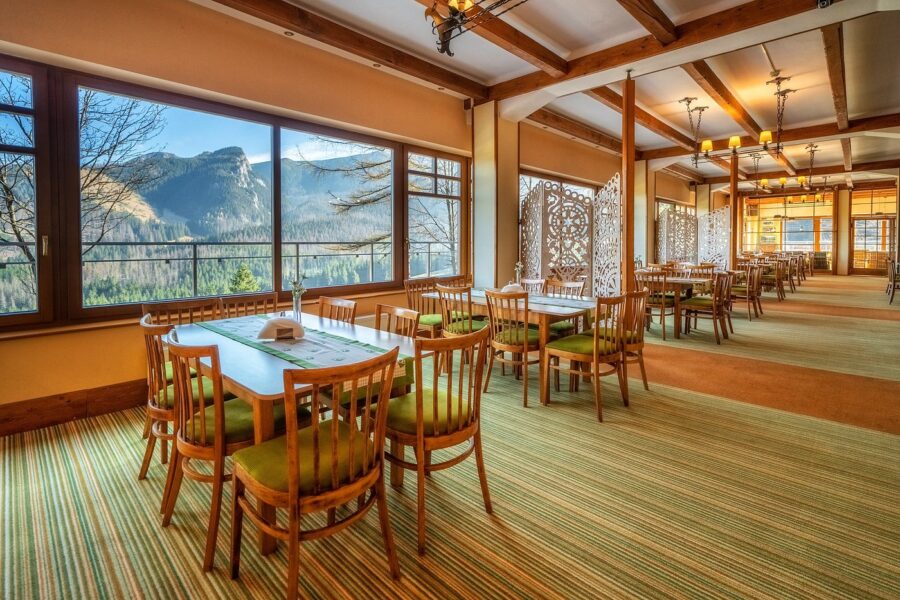 Zakopane mountain-lodge dining room with wooden tables and panoramic mountain view.