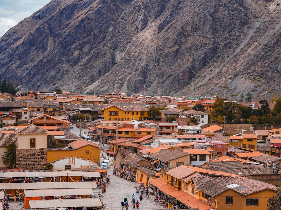 Colorful Ollantaytambo mountain town with traditional market stalls beneath steep rocky Andean cliffs.