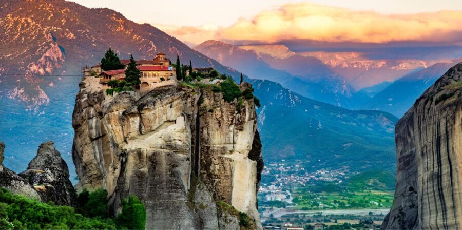Kalambaka Meteora monastery perched on dramatic sandstone pillar above verdant Greek valley.