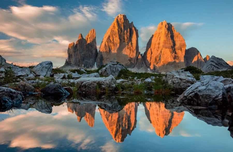 Tre Cime di Lavaredo Dolomites reflected in alpine tarn at golden sunrise.