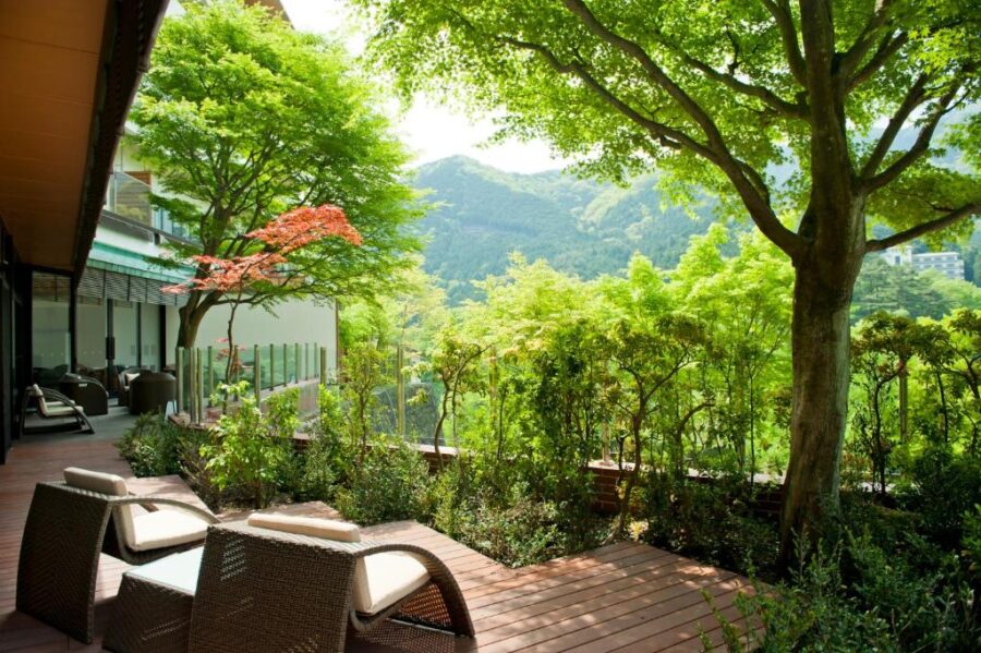 Luxury mountain hotel terrace lounge with rattan chairs, forest views, and relaxing outdoor spa ambiance.