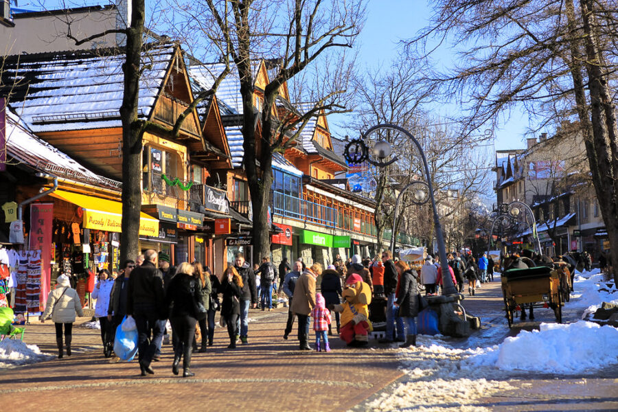 Krupówki Street winter market in Zakopane with wooden chalets and snowy promenade.