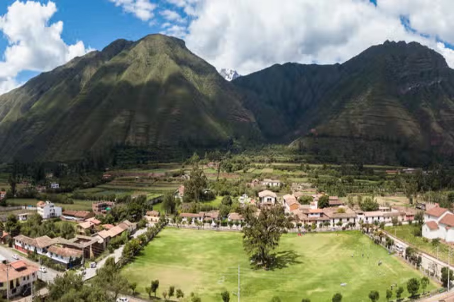 Mountain valley town with green park, farmlands and dramatic Andes mountains in Yucay, Peru.
