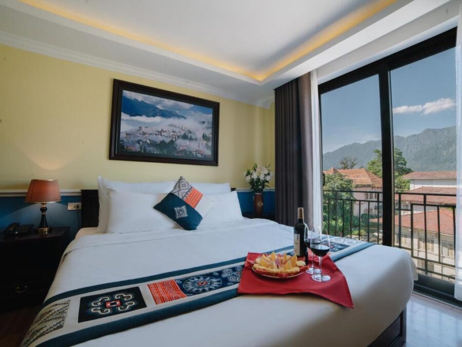 Cozy Sapa mountain view hotel room with balcony, double bed, wine, and scenic landscape.