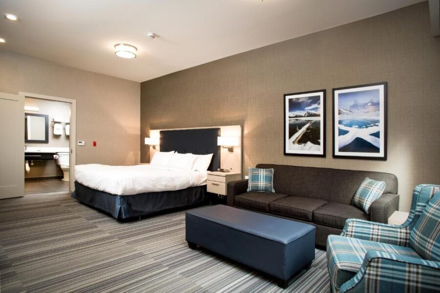 Mountaineer Lodge hotel room with a comfortable bed, inviting couch, and a chair for guests to unwind.

