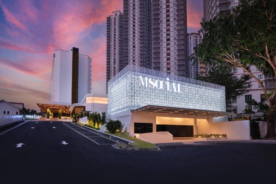 M Social Resort Penang hotel exterior at dusk with modern facade, driveway and city skyline backdrop.