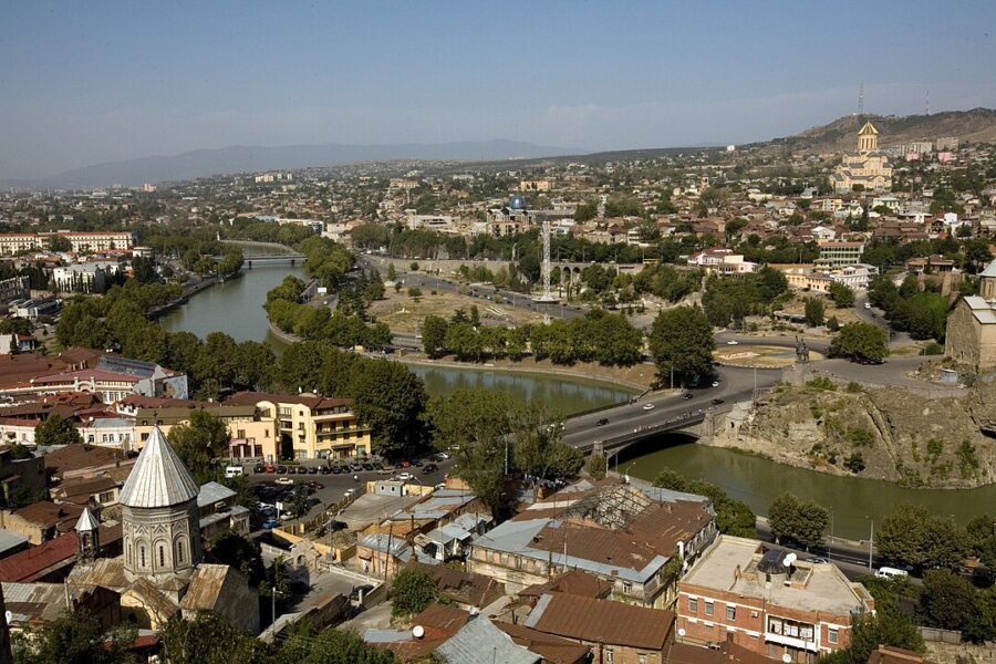 Tbilisi skyline featuring the Mtkvari River and a bridge, showcasing the city's vibrant landscape.
