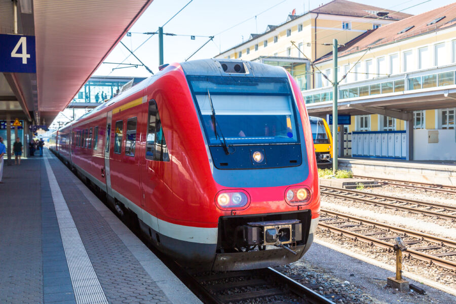 Red train arriving at Munich Hauptbahnhof Central Station in Germany, with passengers waiting on the platform