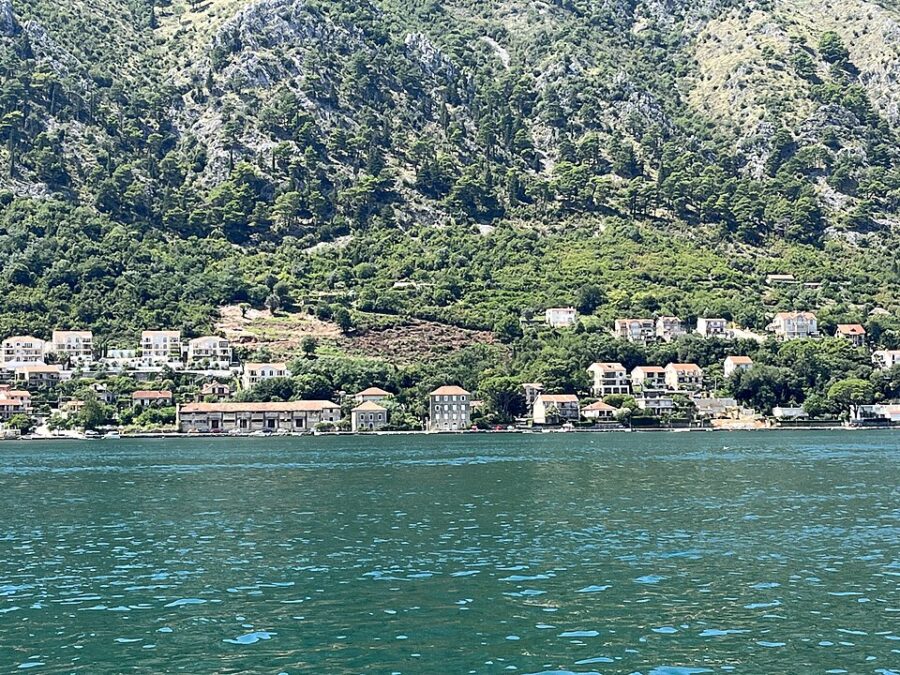 Scenic view of Muo, Montenegro, featuring a mountain range and a picturesque town by the water.