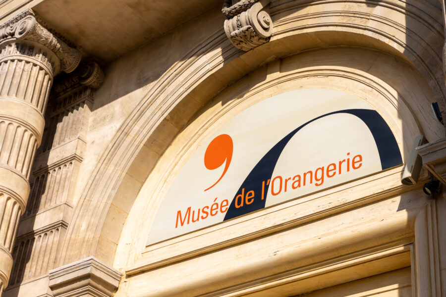 Close-up of the Musée de l'Orangerie sign at the entrance, surrounded by the beautiful Tuileries Garden in Paris.