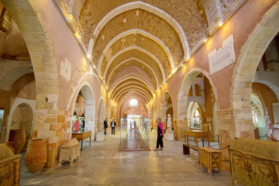 Historic museum interior with arches, artifacts, and engaged visitors exploring cultural heritage.
