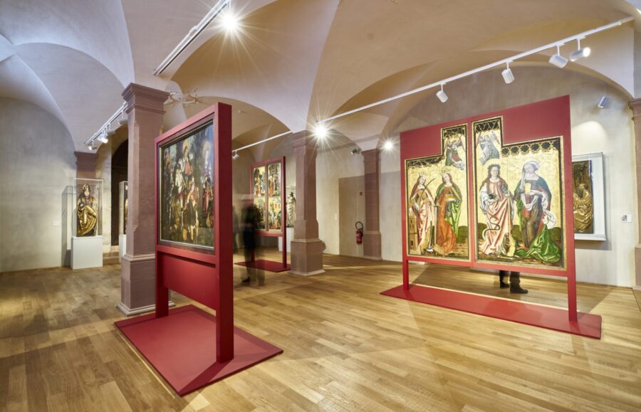 Unterlinden Museum gallery displaying medieval altar panels and triptychs on red stands.