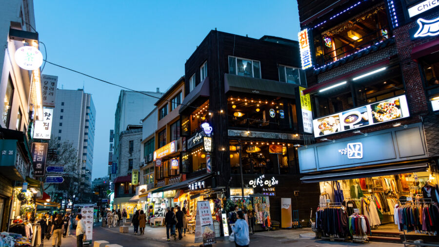 The Myeong-dong area at sundown, filled with shops and a crowd, captures the lively atmosphere of Seoul, South Korea