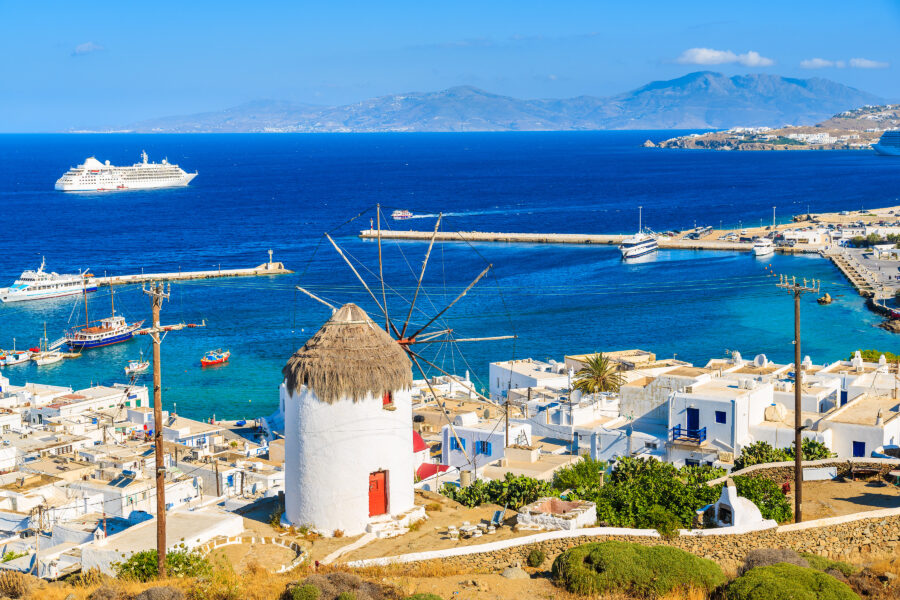 Iconic windmill overlooking Mykonos port, set against the backdrop of the Cyclades islands in Greece's picturesque landscape