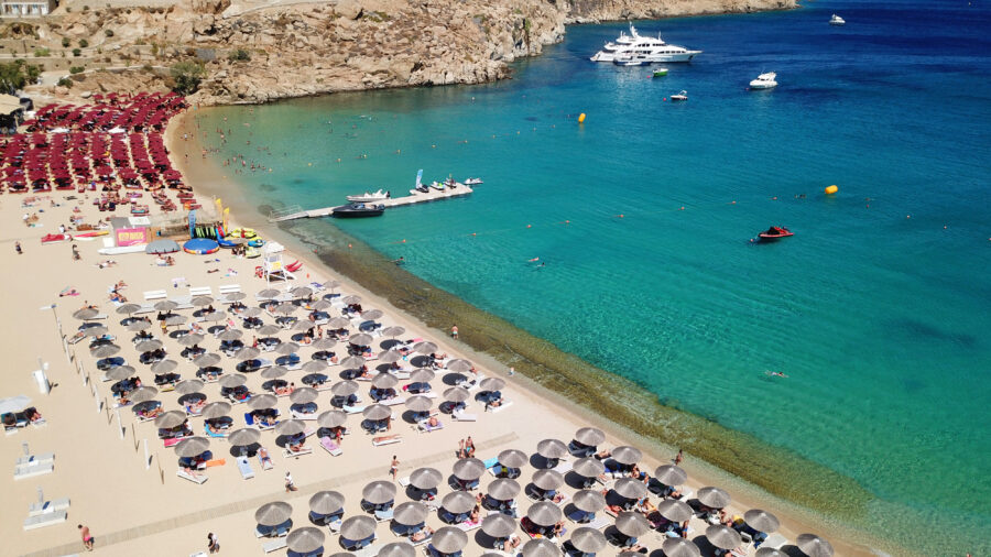Aerial view of Super Paradise Beach in Mykonos, showcasing crowded sandy shores and clear sapphire waters