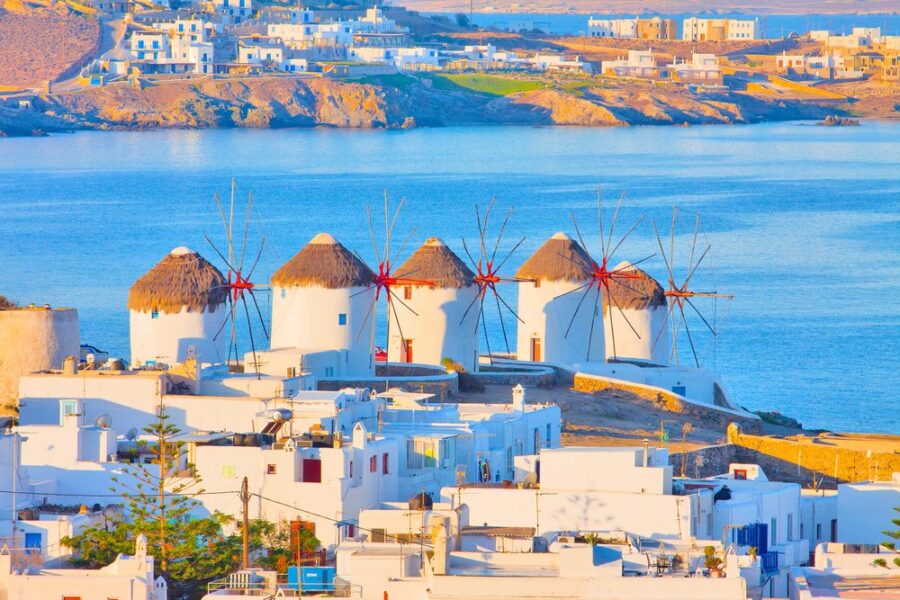 Greek island windmills with calm sea, traditional architecture, and serene landscape in Mykonos.