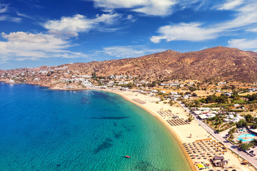 Mylopotas beach in Ios, Greece, showcasing golden sand, turquoise waves, and people relaxing under the sun